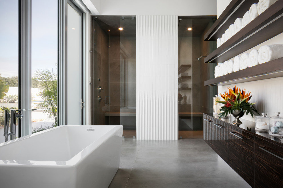 Пример оригинального дизайна: огромная главная ванная комната в современном стиле с плоскими фасадами, темными деревянными фасадами, отдельно стоящей ванной, душем без бортиков, унитазом-моноблоком, серой плиткой, керамогранитной плиткой, белыми стенами, полом из керамогранита, врезной раковиной, столешницей из искусственного кварца, серым полом, душем с распашными дверями, белой столешницей, сиденьем для душа, тумбой под одну раковину, подвесной тумбой и сводчатым потолком