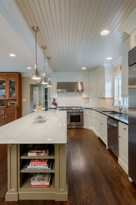 Photo of a transitional open plan kitchen in Charlotte with a farmhouse sink, beaded inset cabinets, white cabinets, granite benchtops, white splashback, ceramic splashback, stainless steel appliances, dark hardwood floors and with island.