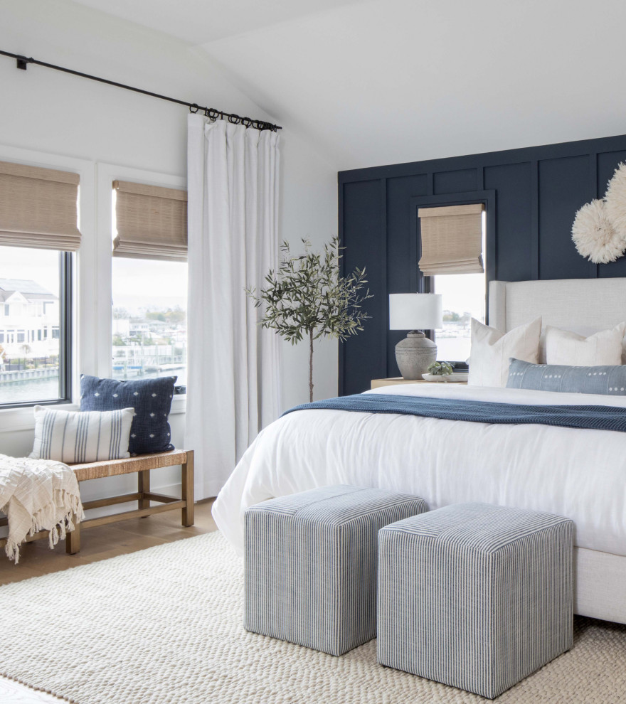 Mid-sized beach style master bedroom in New York with blue walls, medium hardwood floors and panelled walls.