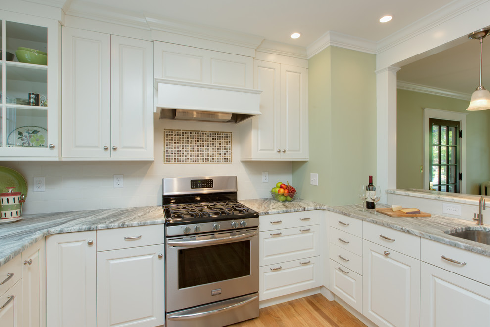 Example of a transitional u-shaped medium tone wood floor eat-in kitchen design in Boston with an undermount sink, raised-panel cabinets, white cabinets, granite countertops, white backsplash, subway tile backsplash and stainless steel appliances