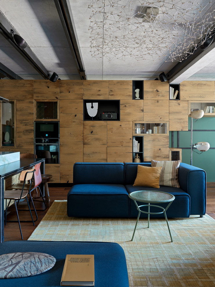 На фото: открытая гостиная комната среднего размера в стиле лофт с паркетным полом среднего тона, мультимедийным центром, коричневым полом, балками на потолке, синим диваном и зелеными стенами с