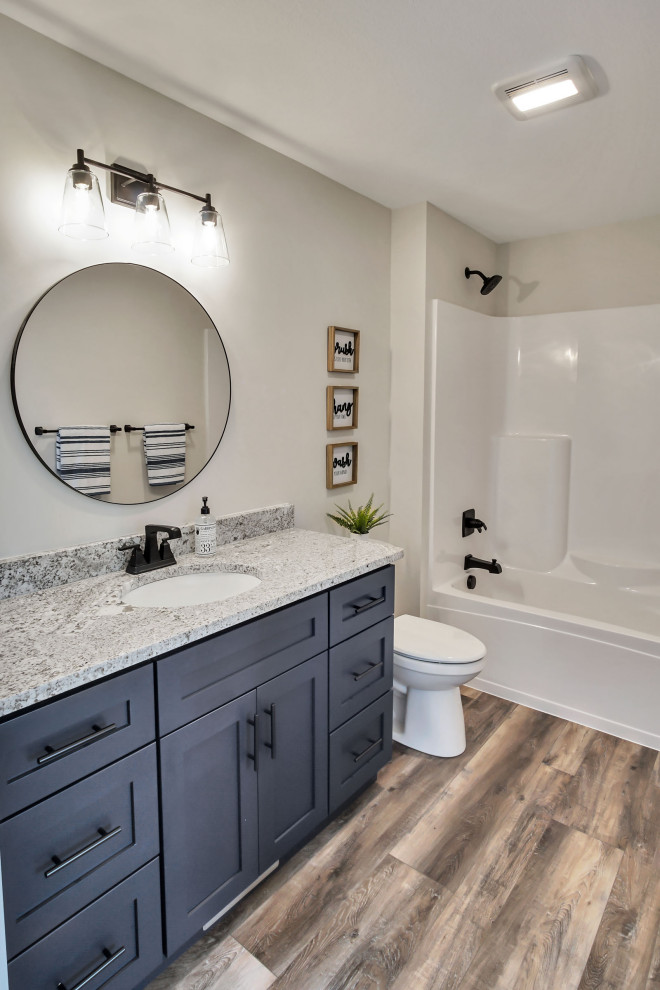 Mid-sized country master bathroom in Other with shaker cabinets, medium wood cabinets, a shower/bathtub combo, a two-piece toilet, grey walls, vinyl floors, an undermount sink, quartzite benchtops, multi-coloured floor, a shower curtain, white benchtops, a single vanity and a built-in vanity.