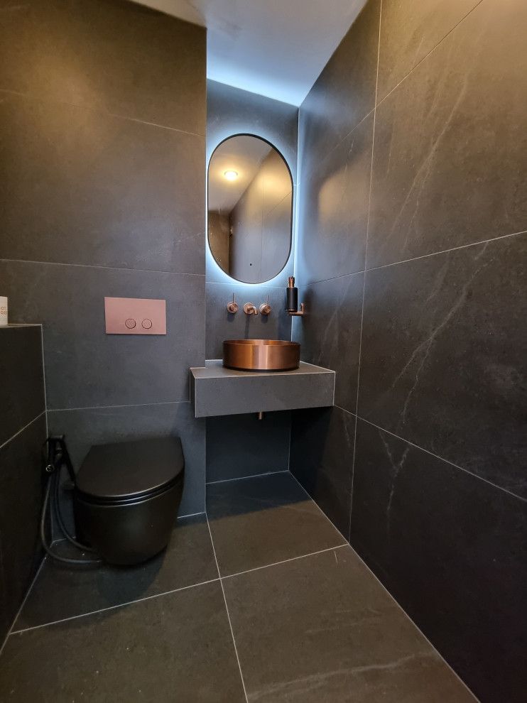 Small contemporary bathroom in Other with black cabinets, a wall-mount toilet, black tile, porcelain tile, black walls, porcelain floors, a vessel sink, tile benchtops, black floor, black benchtops, a single vanity and a floating vanity.
