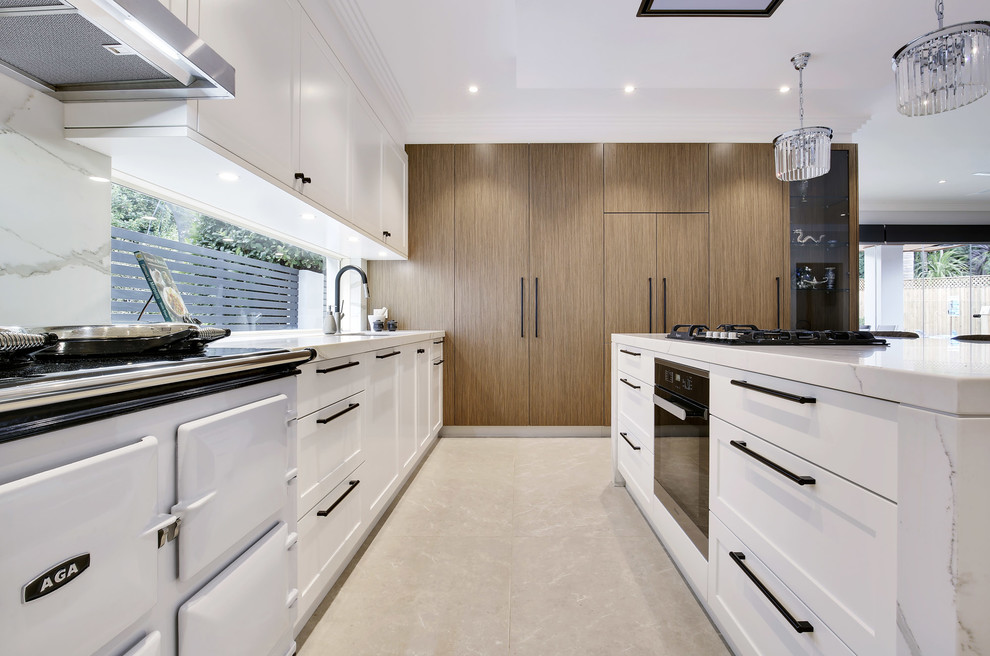 This is an example of a large modern l-shaped eat-in kitchen in Sydney with a double-bowl sink, shaker cabinets, white cabinets, quartz benchtops, white splashback, stone tile splashback, coloured appliances, limestone floors, with island and beige floor.