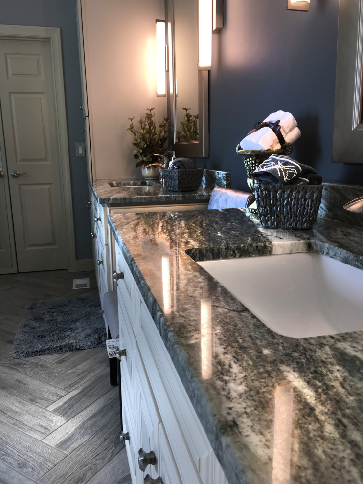 Large transitional master beige tile and ceramic tile porcelain tile and gray floor freestanding bathtub photo in Atlanta with recessed-panel cabinets, yellow cabinets, a two-piece toilet, blue walls, an undermount sink, granite countertops, a hinged shower door and multicolored countertops