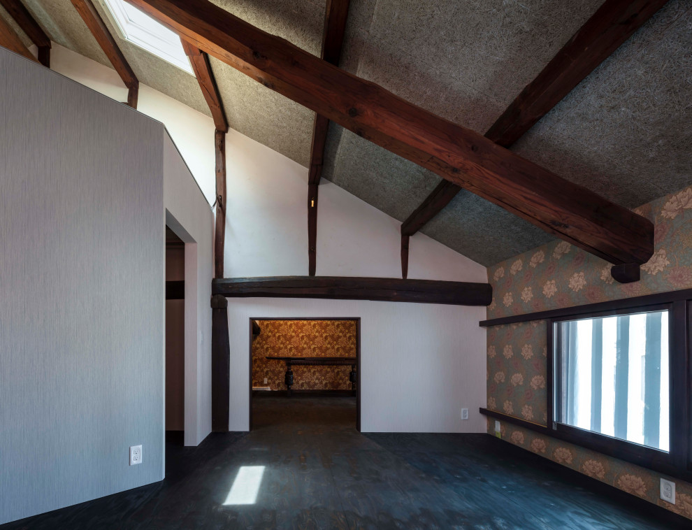 На фото: хозяйская спальня среднего размера в восточном стиле с серыми стенами, полом из фанеры, черным полом, балками на потолке и обоями на стенах без камина