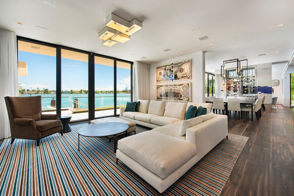 Photo of an expansive contemporary open concept living room in Miami with white walls, dark hardwood floors and brown floor.