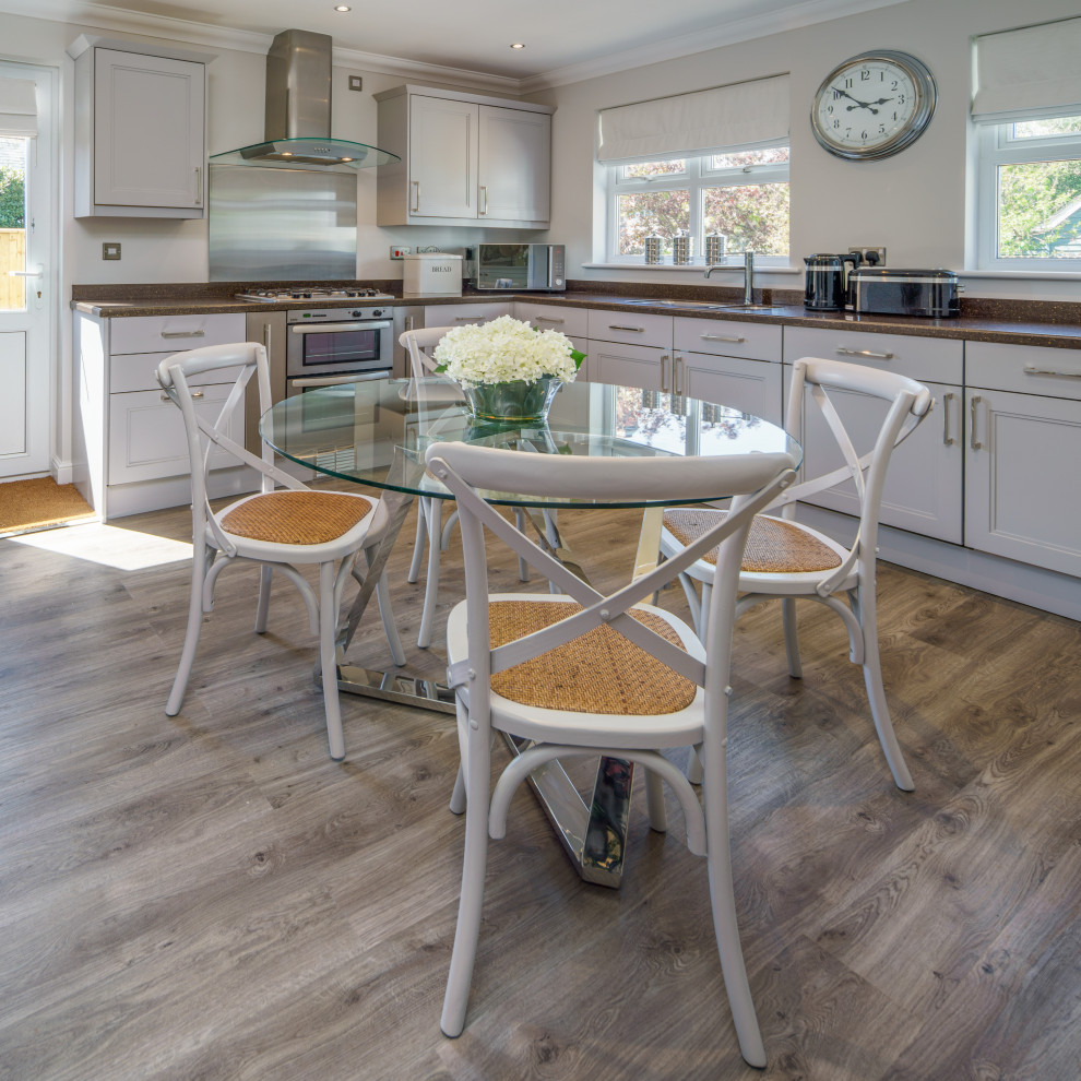 Eat-in kitchen - mid-sized contemporary u-shaped laminate floor and brown floor eat-in kitchen idea in Other with shaker cabinets, gray cabinets, granite countertops, metallic backsplash, black appliances, no island and black countertops
