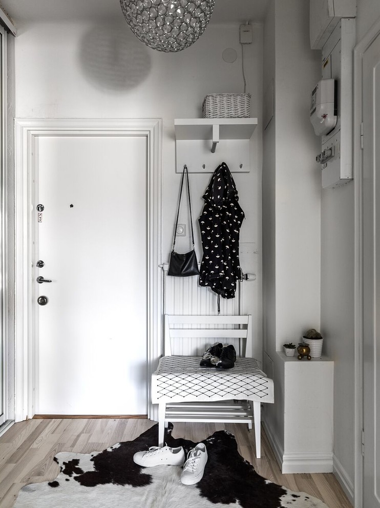 This is an example of a small scandinavian entryway in Stockholm with white walls and light hardwood floors.