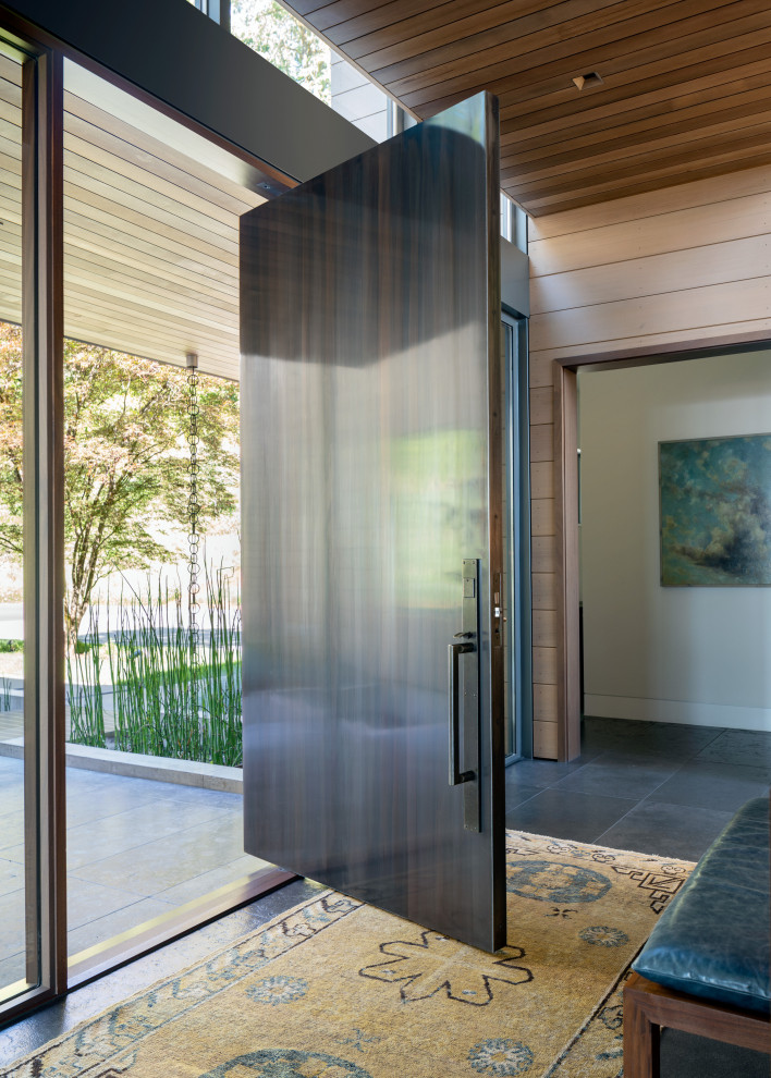 На фото: прихожая в стиле модернизм с поворотной входной дверью, коричневой входной дверью и деревянным потолком