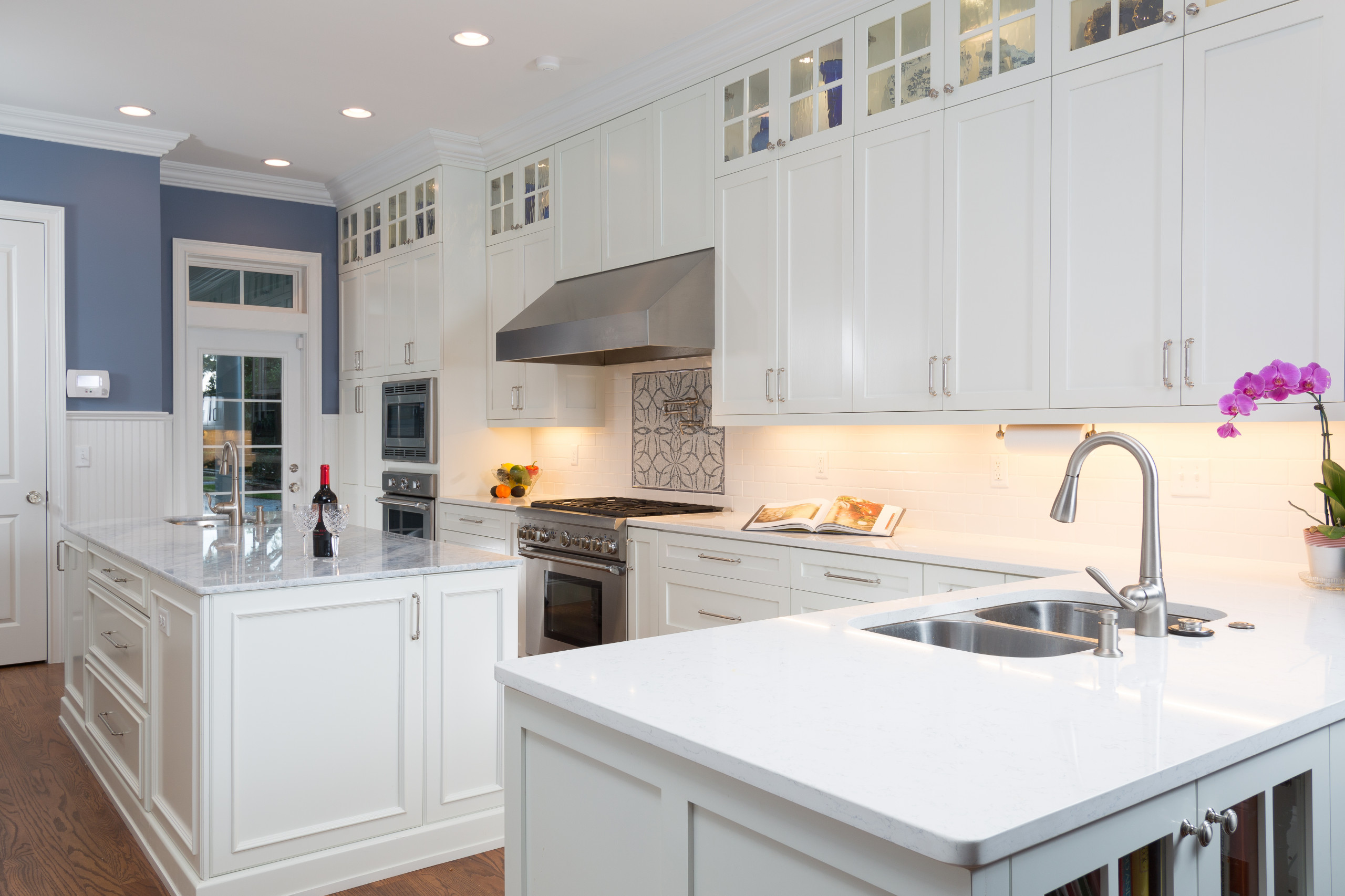 Inspiration for a timeless medium tone wood floor kitchen remodel in Jacksonville with a double-bowl sink, white backsplash, subway tile backsplash, stainless steel appliances and an island