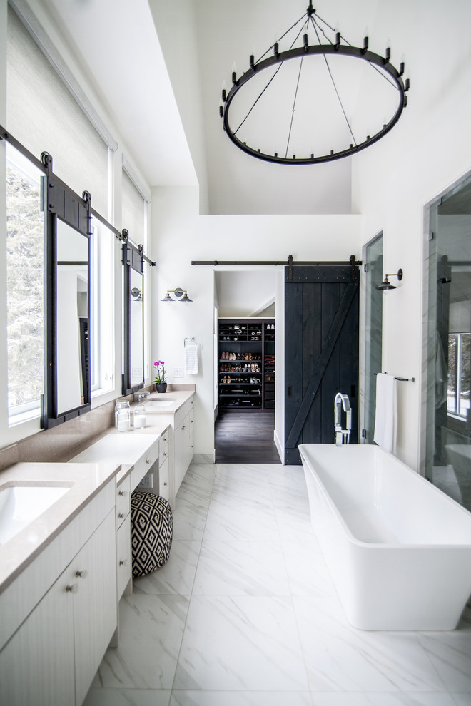 This is an example of a country master bathroom in Calgary with flat-panel cabinets, white cabinets, a freestanding tub, white walls, an undermount sink and white floor.