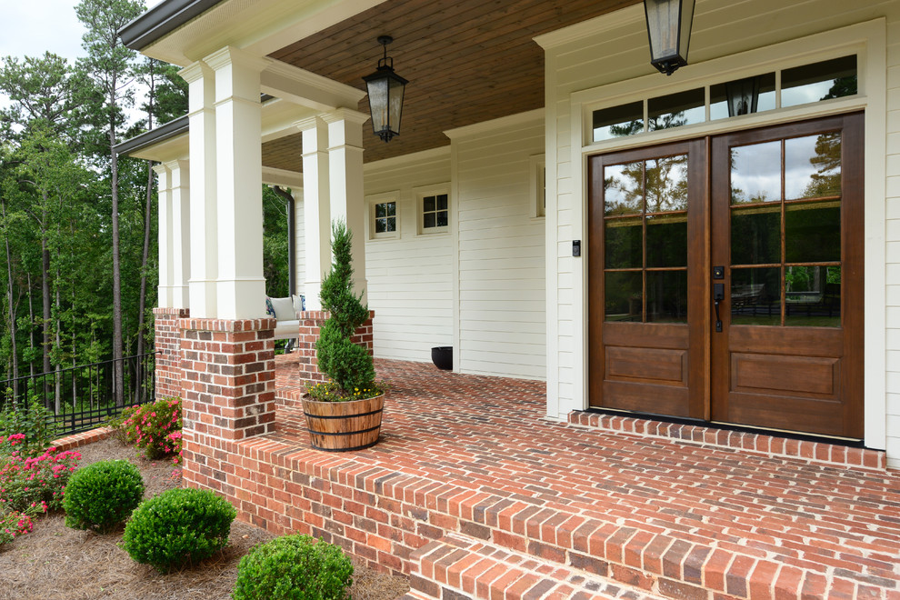 Inspiration for a country front door in Atlanta with white walls, a double front door, a medium wood front door and red floor.