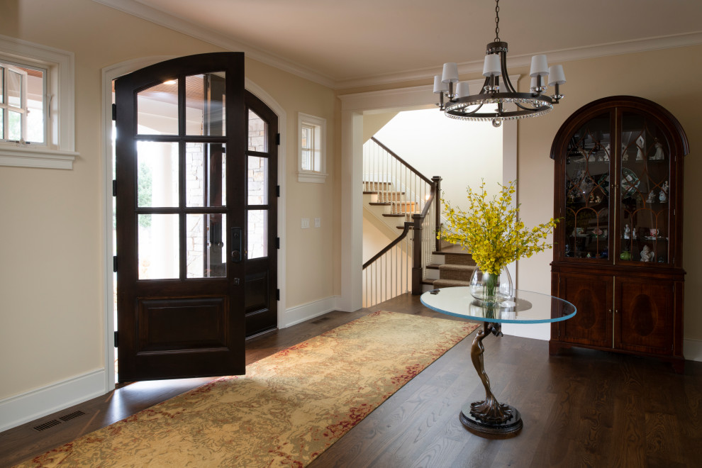 This is an example of a large traditional foyer in Minneapolis with brown walls, dark hardwood floors, a double front door, a dark wood front door and brown floor.