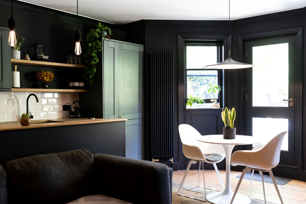 Moderne Wohnküche mit schwarzer Wandfarbe und braunem Holzboden in London