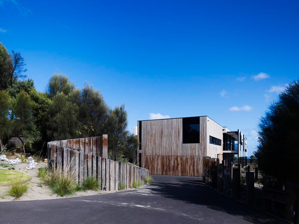 Photo of a large contemporary two-storey black exterior in Melbourne with wood siding and a flat roof.