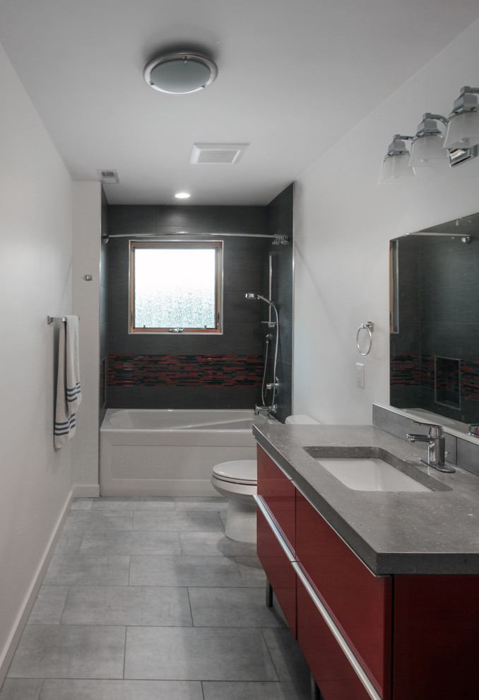 This is an example of a mid-sized contemporary 3/4 bathroom in DC Metro with an undermount sink, flat-panel cabinets, red cabinets, concrete benchtops, an alcove tub, a shower/bathtub combo, a two-piece toilet, brown tile, ceramic tile, white walls and ceramic floors.