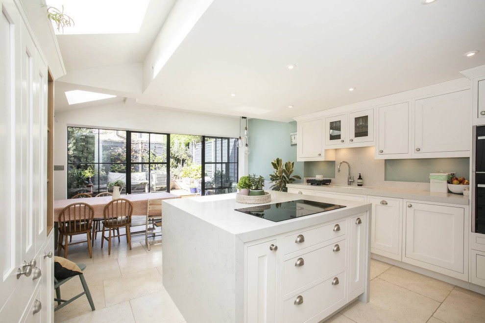 This is an example of a mid-sized contemporary u-shaped eat-in kitchen in London with shaker cabinets, white cabinets, quartz benchtops and with island.