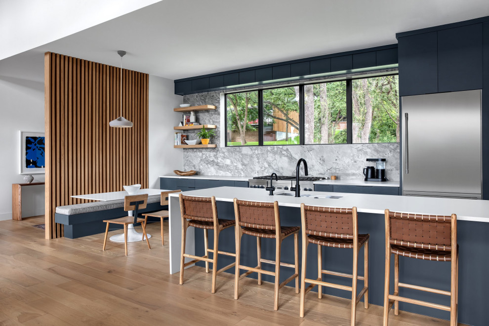 Photo of a large midcentury galley eat-in kitchen in Austin with an undermount sink, flat-panel cabinets, blue cabinets, quartz benchtops, grey splashback, marble splashback, stainless steel appliances, light hardwood floors, a peninsula and white benchtop.
