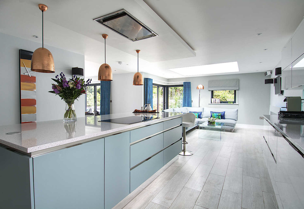 Design ideas for a large contemporary galley open plan kitchen in Hampshire with an integrated sink, flat-panel cabinets, white cabinets, solid surface benchtops, blue splashback, glass sheet splashback, stainless steel appliances, porcelain floors, with island and grey floor.