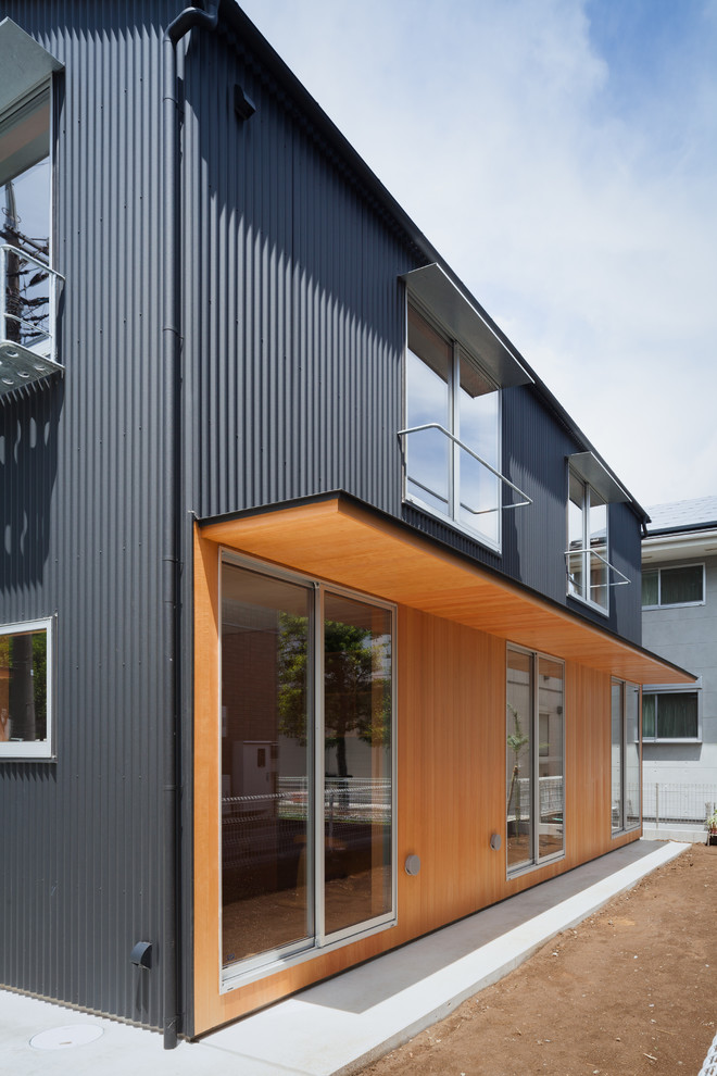 Photo of a mid-sized modern two-storey black house exterior with metal siding, a shed roof and a metal roof.