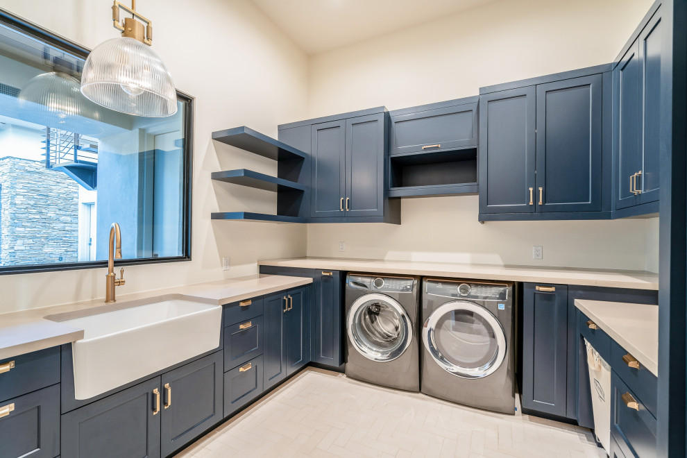 Large contemporary u-shaped dedicated laundry room in Phoenix with a farmhouse sink, shaker cabinets, blue cabinets, quartzite benchtops, beige walls, porcelain floors, a side-by-side washer and dryer, white floor, beige benchtop and vaulted.