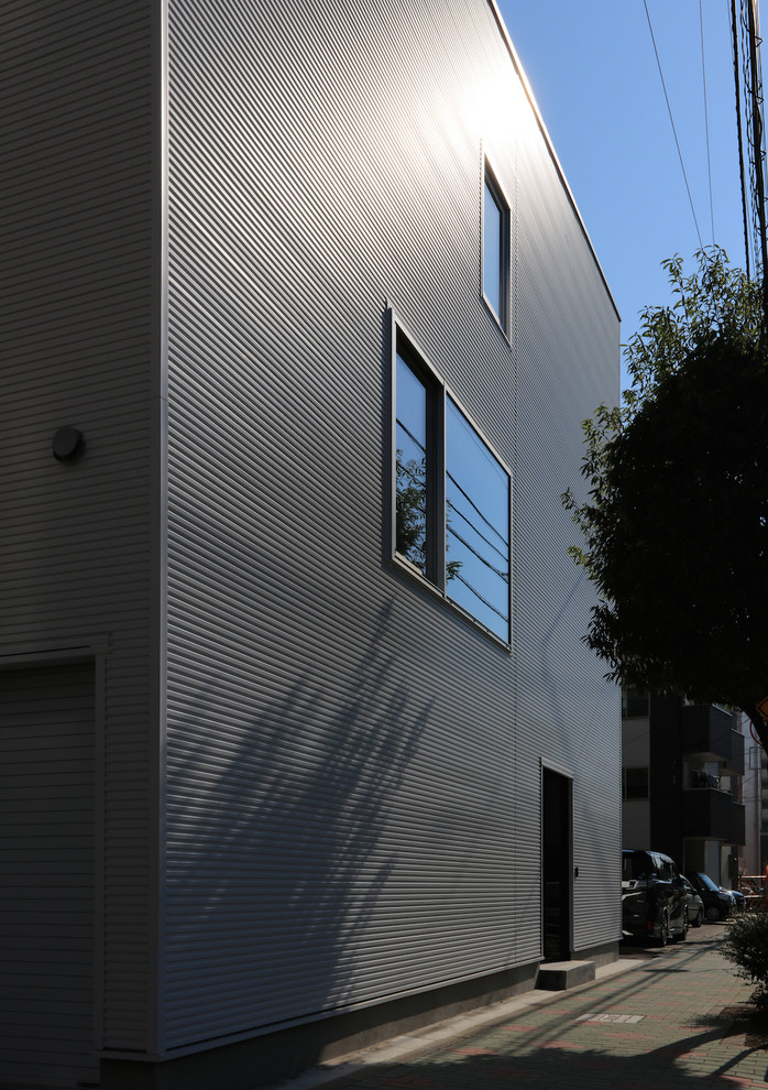This is an example of a modern three-storey white house exterior in Tokyo with metal siding, a mixed roof and a gambrel roof.