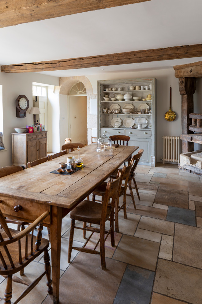 Photo of a country dining room in Gloucestershire with beige walls, multi-coloured floors and exposed beams.