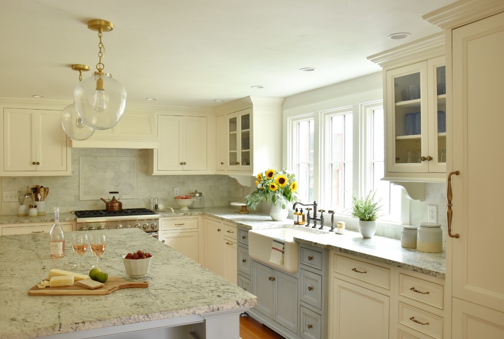 Design ideas for a country l-shaped kitchen in Boston with a farmhouse sink, granite benchtops, marble splashback, panelled appliances, with island, recessed-panel cabinets, white cabinets, grey splashback, medium hardwood floors, brown floor and grey benchtop.