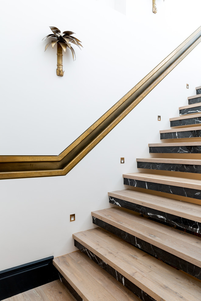 Design ideas for a mid-sized eclectic wood straight staircase in London with marble risers and metal railing.
