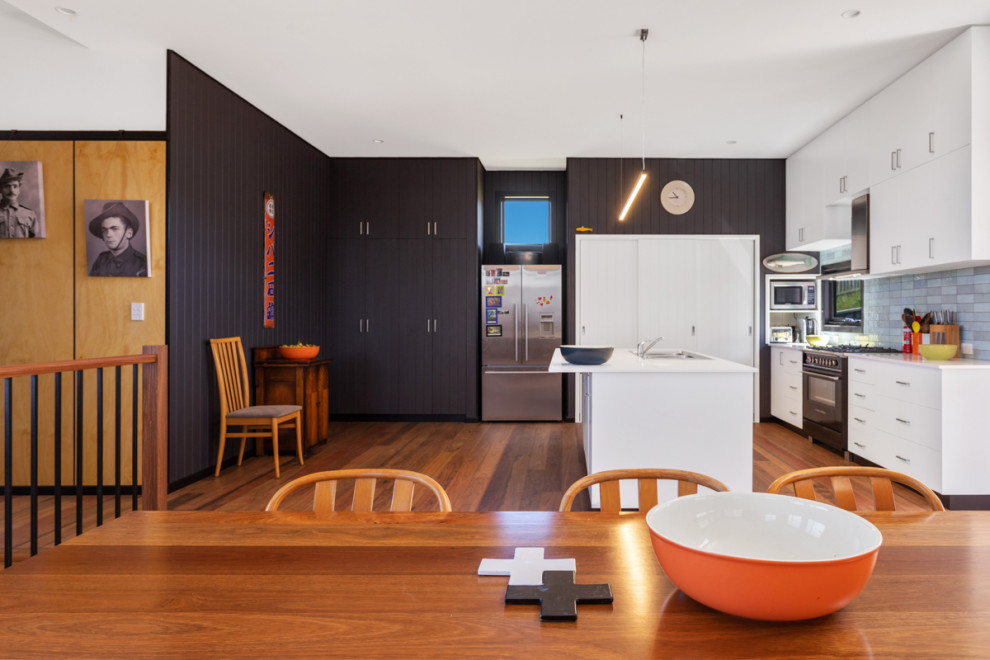 Photo of a mid-sized contemporary kitchen/dining combo in Other with grey walls, dark hardwood floors, brown floor, vaulted and panelled walls.