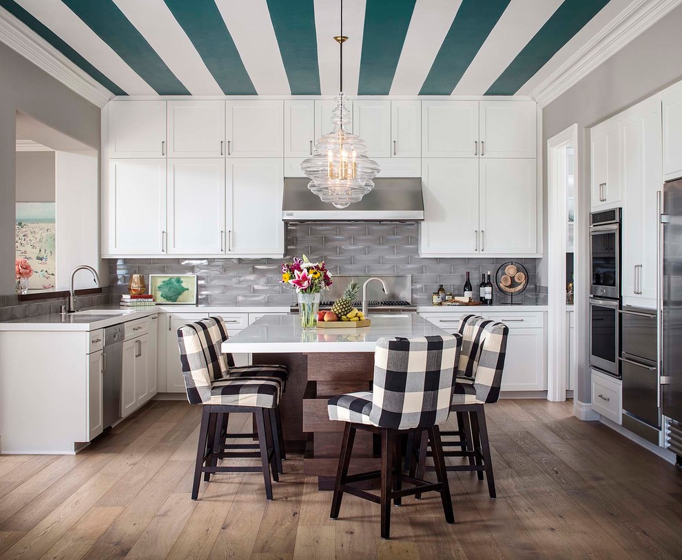 Inspiration for a transitional u-shaped kitchen in San Diego with with island, an undermount sink, shaker cabinets, white cabinets, grey splashback, subway tile splashback, stainless steel appliances, dark hardwood floors and brown floor.