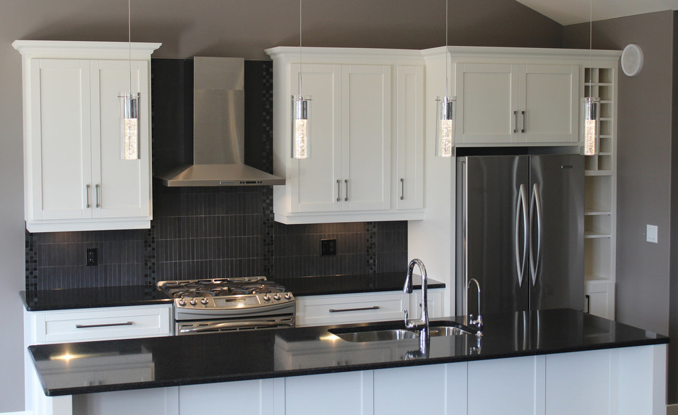 Open concept kitchen - mid-sized transitional galley open concept kitchen idea with a double-bowl sink, shaker cabinets, white cabinets, quartz countertops, gray backsplash, porcelain backsplash, stainless steel appliances, an island and black countertops