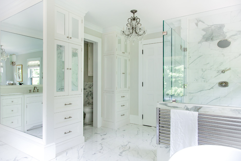 This is an example of an expansive traditional master bathroom in Boston with flat-panel cabinets, white cabinets, marble benchtops, a claw-foot tub, a corner shower, white tile, stone tile, beige walls and marble floors.