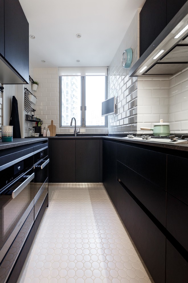 Photo of a small modern u-shaped open plan kitchen in Hong Kong with a double-bowl sink, dark wood cabinets, black splashback, black appliances, ceramic floors, limestone benchtops and subway tile splashback.