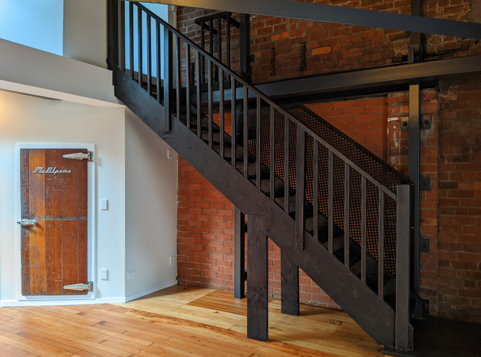 На фото: большой коридор в стиле лофт с коричневыми стенами, коричневым полом и кирпичными стенами с