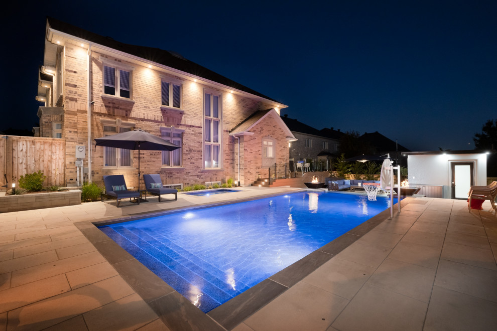 Example of a mid-sized transitional backyard concrete paver and rectangular infinity pool landscaping design in Toronto