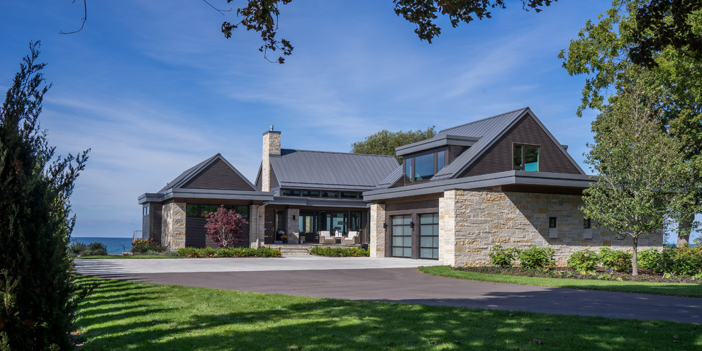 Contemporary two-storey beige house exterior in Grand Rapids with stone veneer and a metal roof.