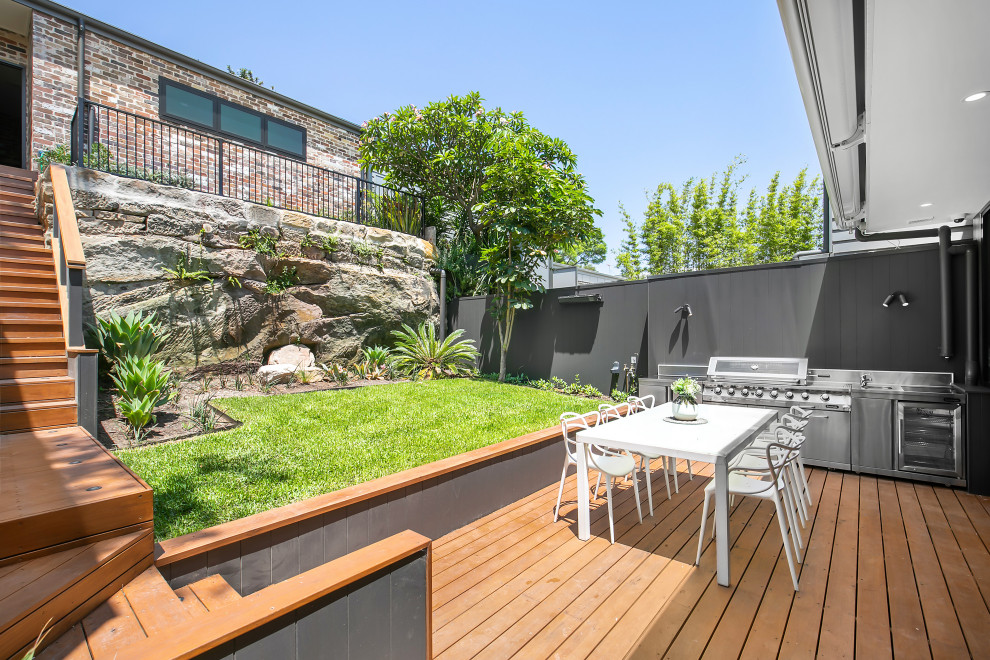 Trendy backyard ground level deck photo in Sydney with an awning