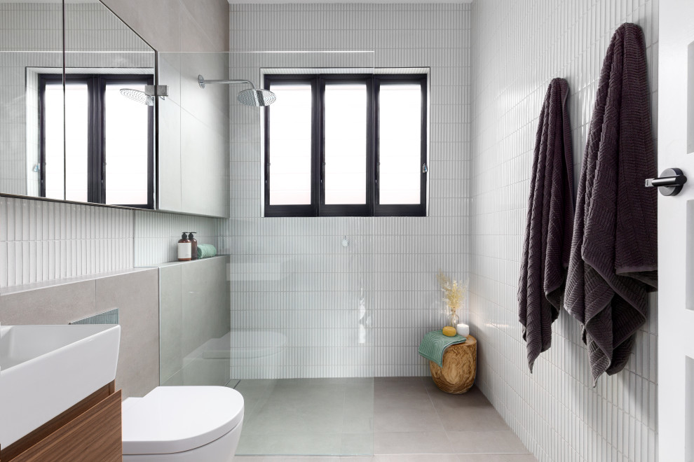 This is an example of a small contemporary ensuite bathroom in Sydney with flat-panel cabinets, medium wood cabinets, a walk-in shower, a one-piece toilet, white tiles, white walls, an integrated sink, grey floors, an open shower, white worktops, a single sink and a floating vanity unit.