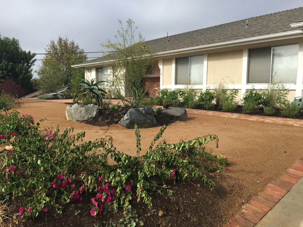 This is an example of a mid-sized traditional front yard full sun xeriscape in Los Angeles with brick pavers.