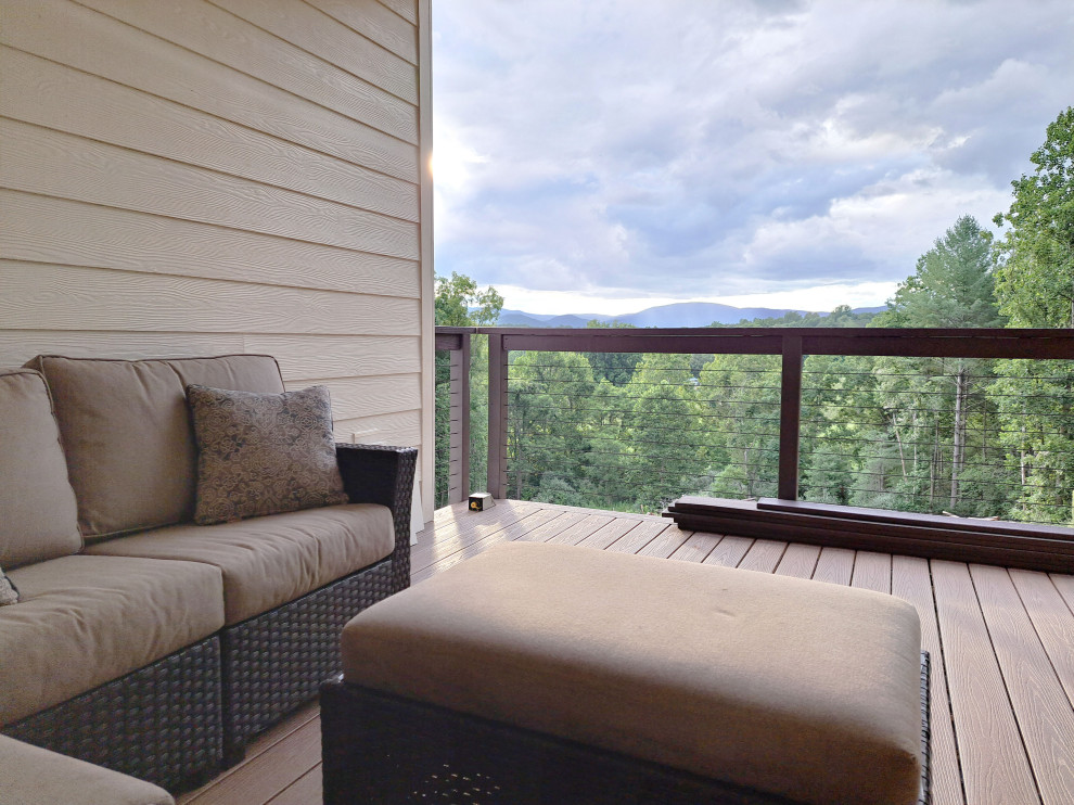 Inspiration for a farmhouse backyard second story privacy and cable railing deck remodel with a roof extension