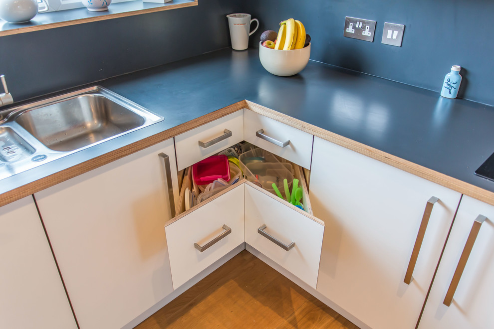Photo of a contemporary l-shaped eat-in kitchen in Sussex with an undermount sink, flat-panel cabinets, white cabinets, laminate benchtops, blue splashback and dark hardwood floors.