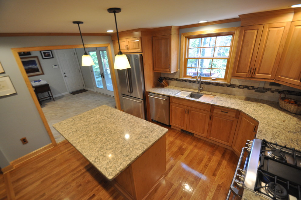 This is an example of a mid-sized traditional l-shaped eat-in kitchen in Boston with an undermount sink, raised-panel cabinets, light wood cabinets, quartz benchtops, beige splashback, ceramic splashback, stainless steel appliances, light hardwood floors, with island and red floor.