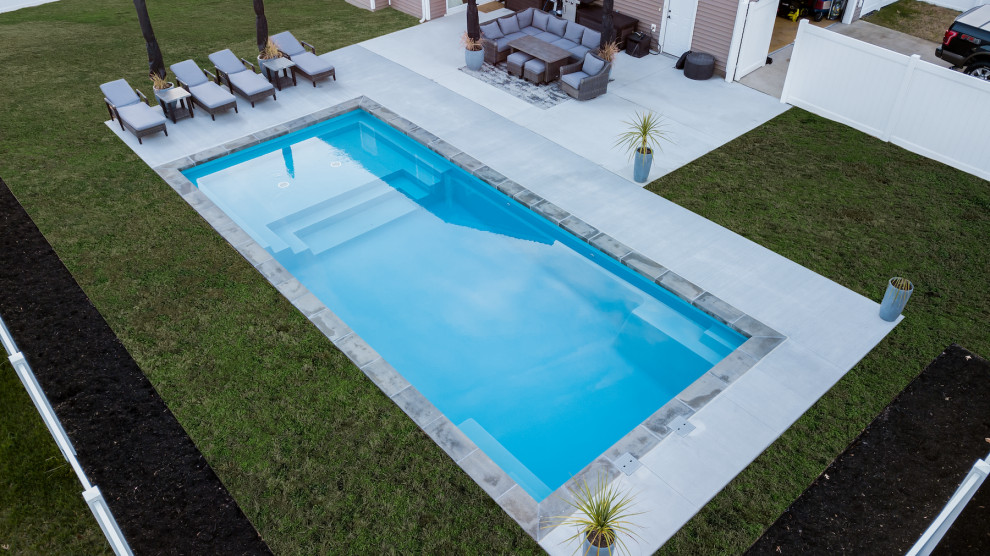 Foto de piscina alargada actual grande rectangular en patio trasero con paisajismo de piscina y adoquines de ladrillo