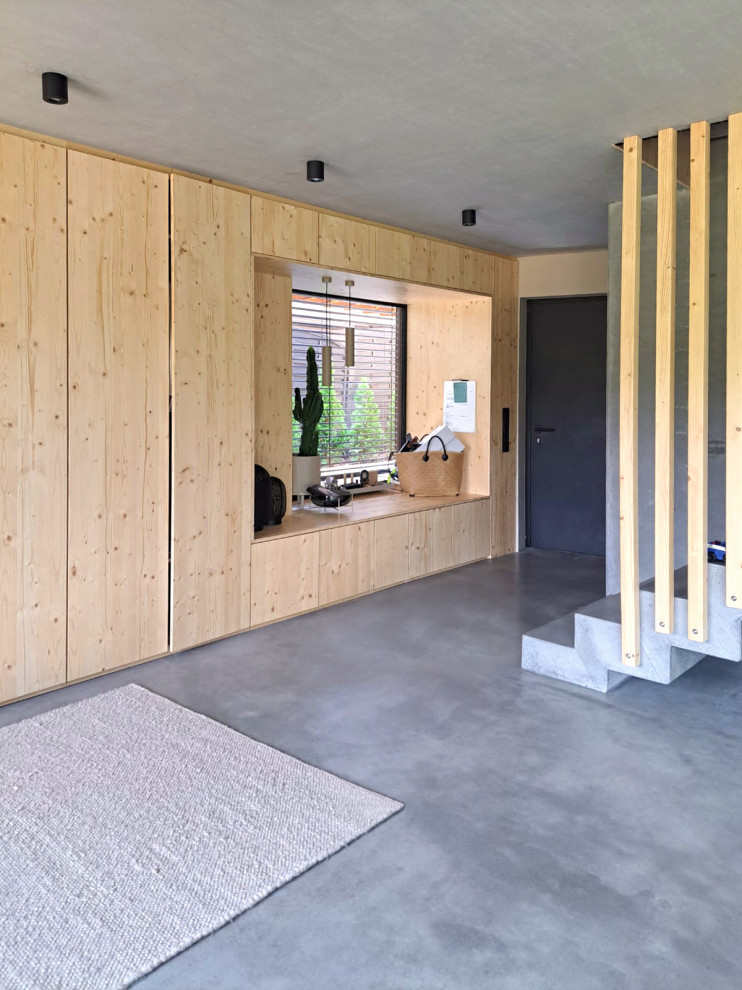 Geräumiger Moderner Eingang mit grauer Wandfarbe, Betonboden, Einzeltür, grauer Haustür, grauem Boden, Holzwänden und Treppe in Frankfurt am Main