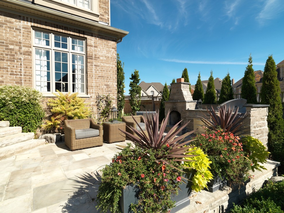Inspiration for a mid-sized contemporary backyard patio in Toronto with an outdoor kitchen and natural stone pavers.