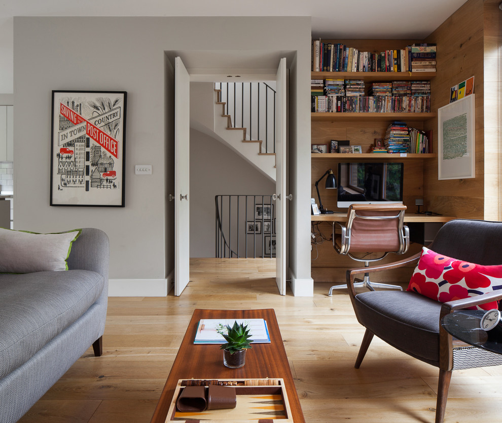 This is an example of a small scandinavian open concept living room in London with grey walls, light hardwood floors, a ribbon fireplace, a plaster fireplace surround and brown floor.