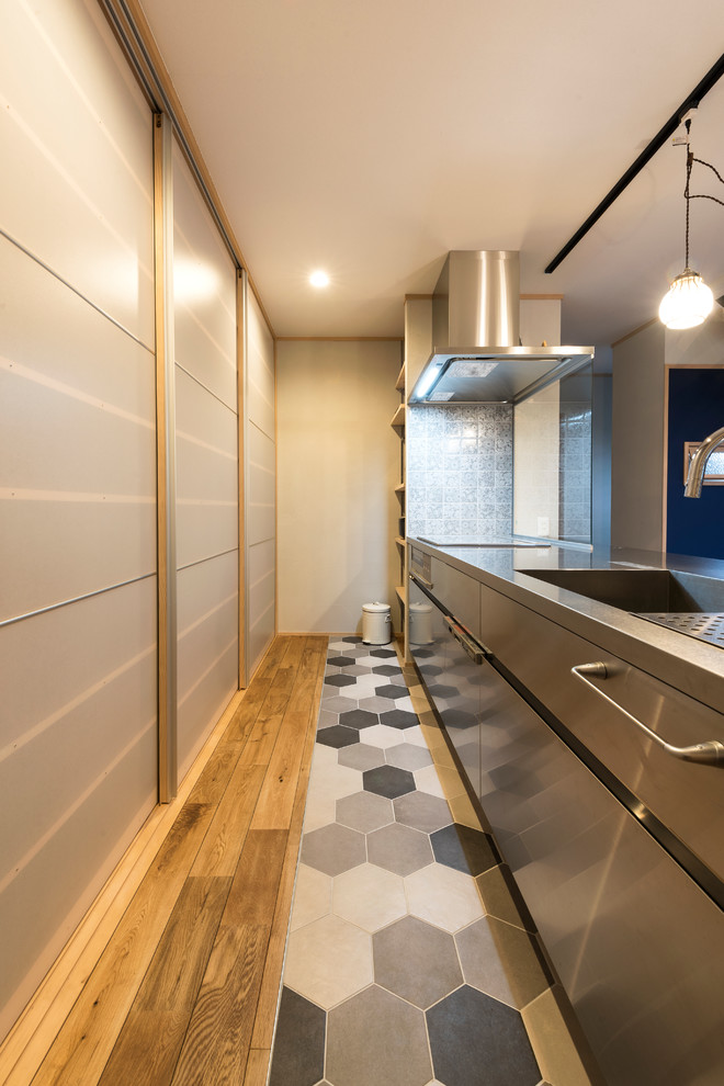 Design ideas for a midcentury single-wall kitchen in Fukuoka with a single-bowl sink, flat-panel cabinets, stainless steel cabinets, stainless steel benchtops, medium hardwood floors and brown floor.