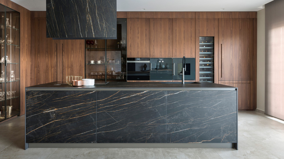 Photo of a mid-sized modern u-shaped eat-in kitchen in Los Angeles with an integrated sink, flat-panel cabinets, orange cabinets, solid surface benchtops, black splashback, marble splashback, black appliances, cement tiles, with island and grey floor.